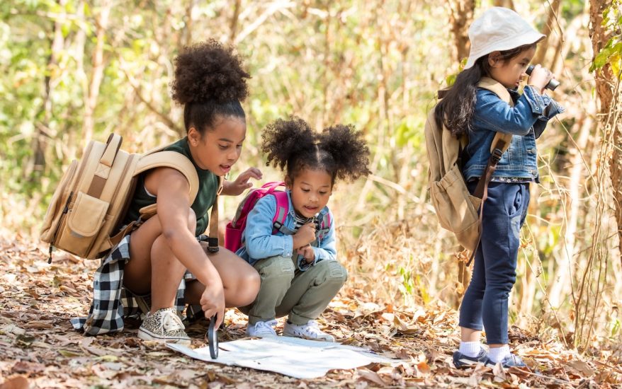three small children in the woods exploring nature